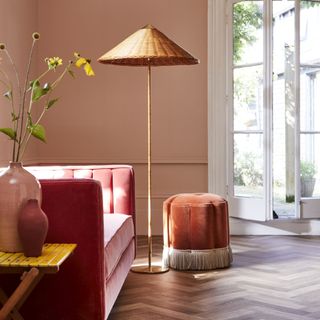 a pink living space with hot pink booth, pink walls, a pink pouffee, a gold lamp and wooden floors