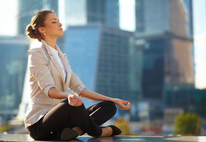 woman meditates in city