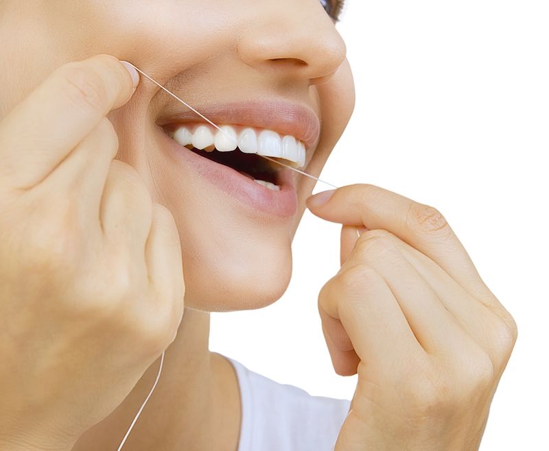 A woman flosses her teeth