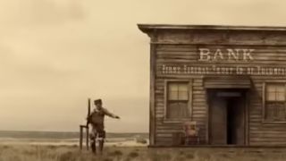 A man running towards the camera from the side of an old bank building in The Ballad of Buster Scruggs