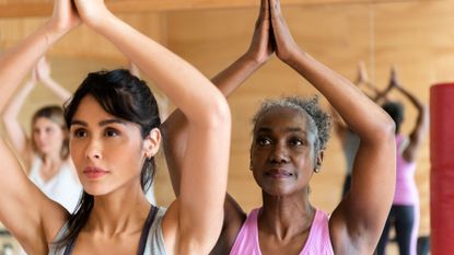 Yoga myths: Two women, one younger and one older, raise their arms in a yoga pose