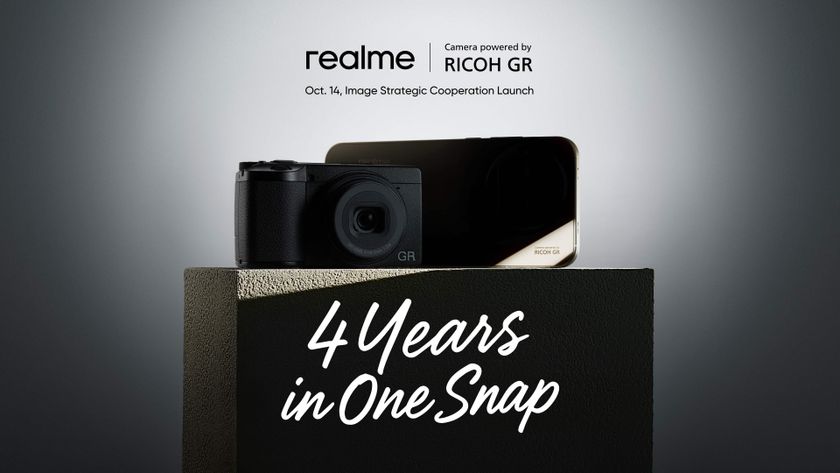 A compact digital Ricoh GR camera next to a mystery Realme smartphone in the shadows