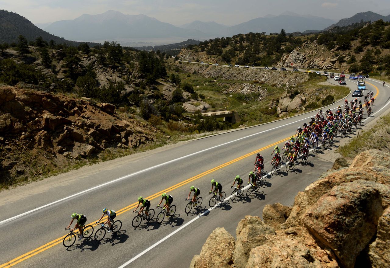 The peloton is lined out on a climb