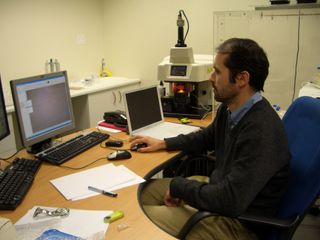 Petrus le Roux observes the close-up image of hominin tooth that is being measured with the laser (laser and mass spectrometer can be seen in background).