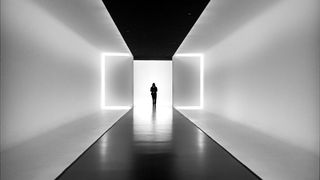 Silhouetted figure in a minimalist corridor with bright rectangular light frames