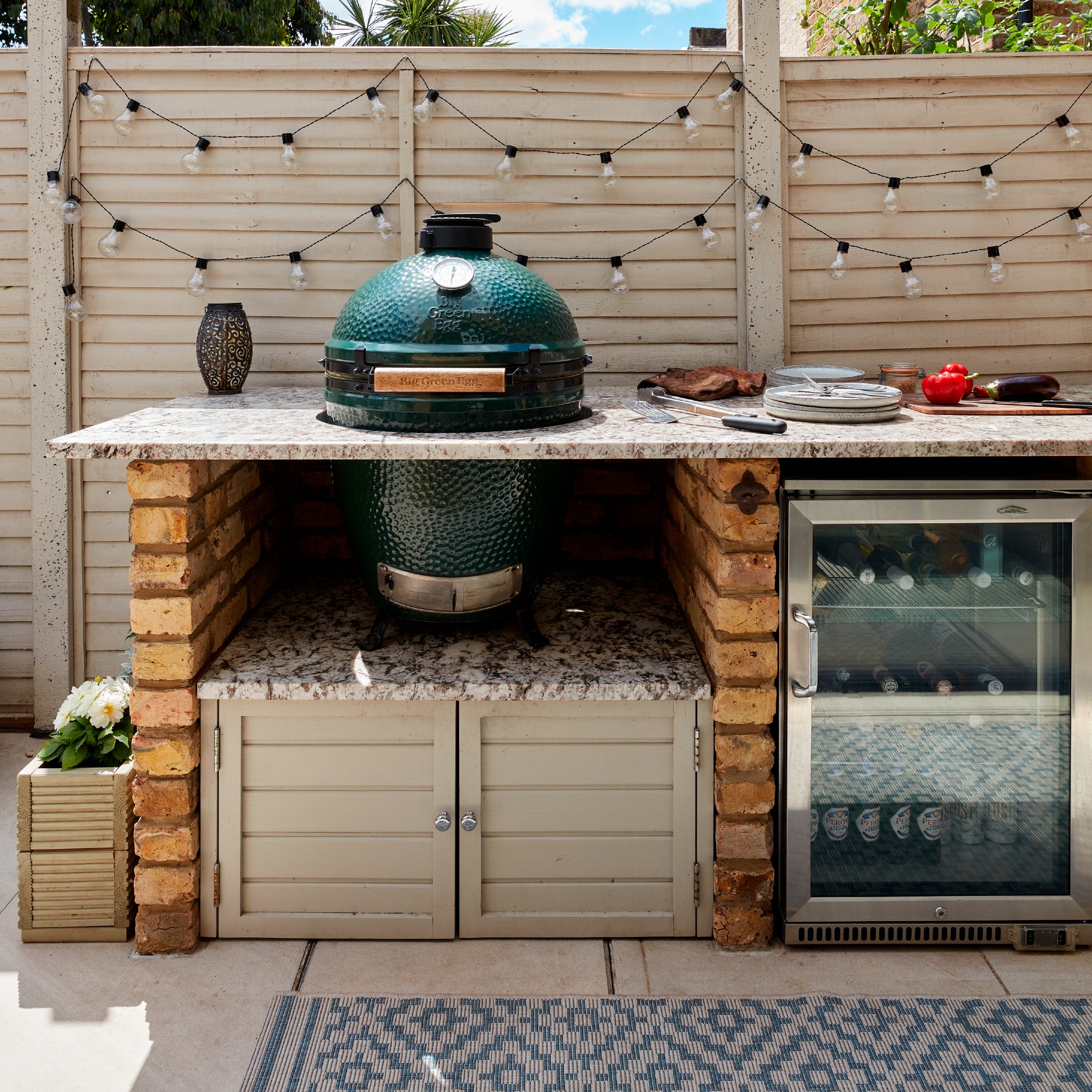 An outdoor kitchen on a patio with string lights decorating the fence