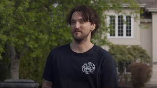 Richard Harmon in a blue tee with body piercings standing in the street in Final Destination: Bloodlines.