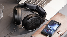 FiiO JT7 headphones on a desk next to a computer and portable audio player