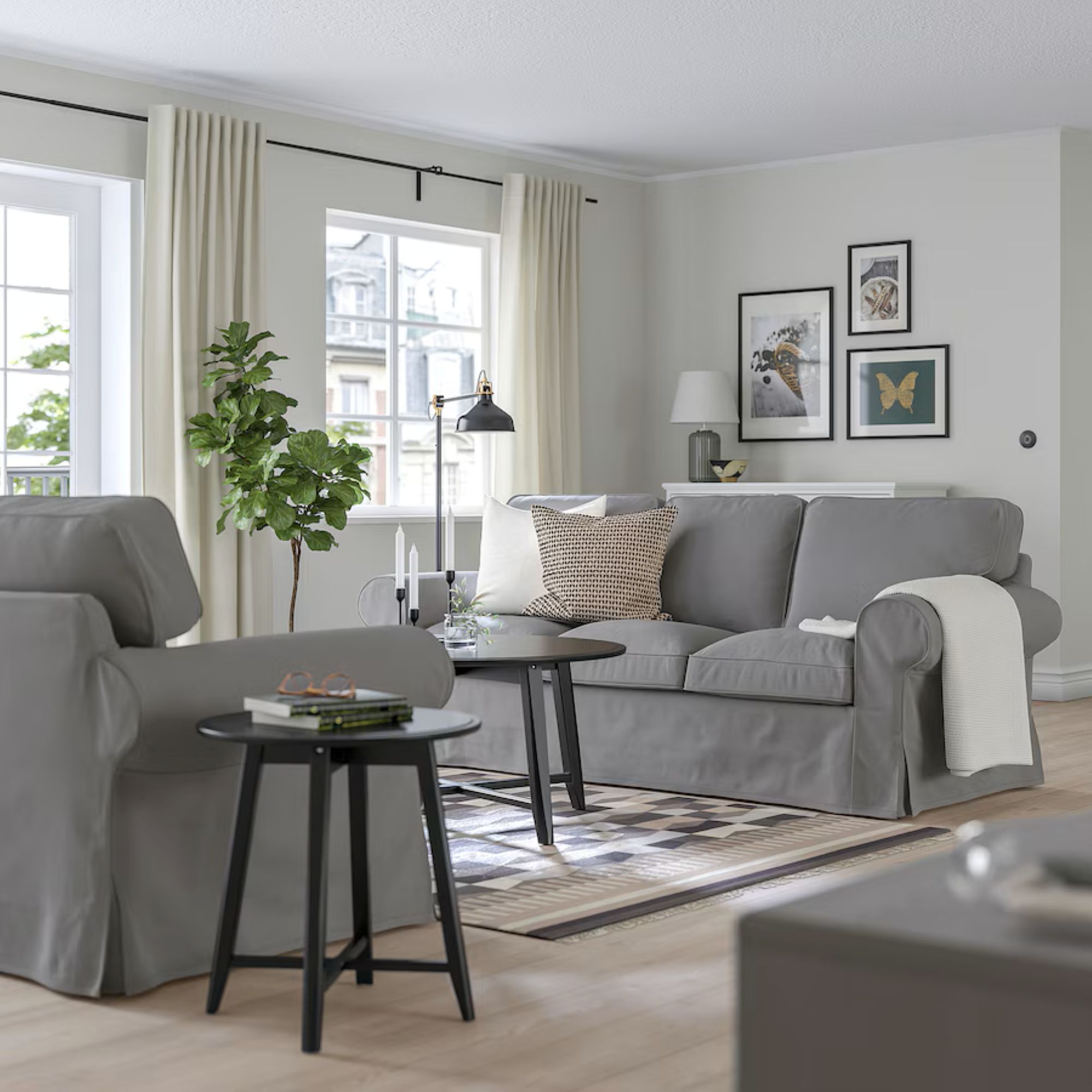 a living room with two grey sofas, a black accent table and a black coffee table