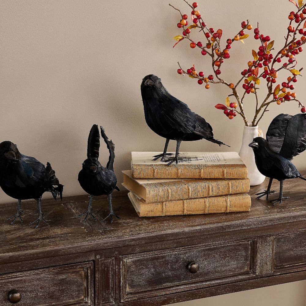 Four lifelike raven decorations on a console table