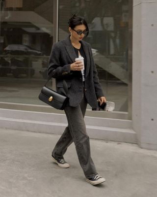 @michellelin.lin wears black Converse high-top trainers with grey jeans and a blazer whilst crossing the pavement