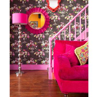 living area with pink sofa and stair case and pink lamp and flower wallpaper wall