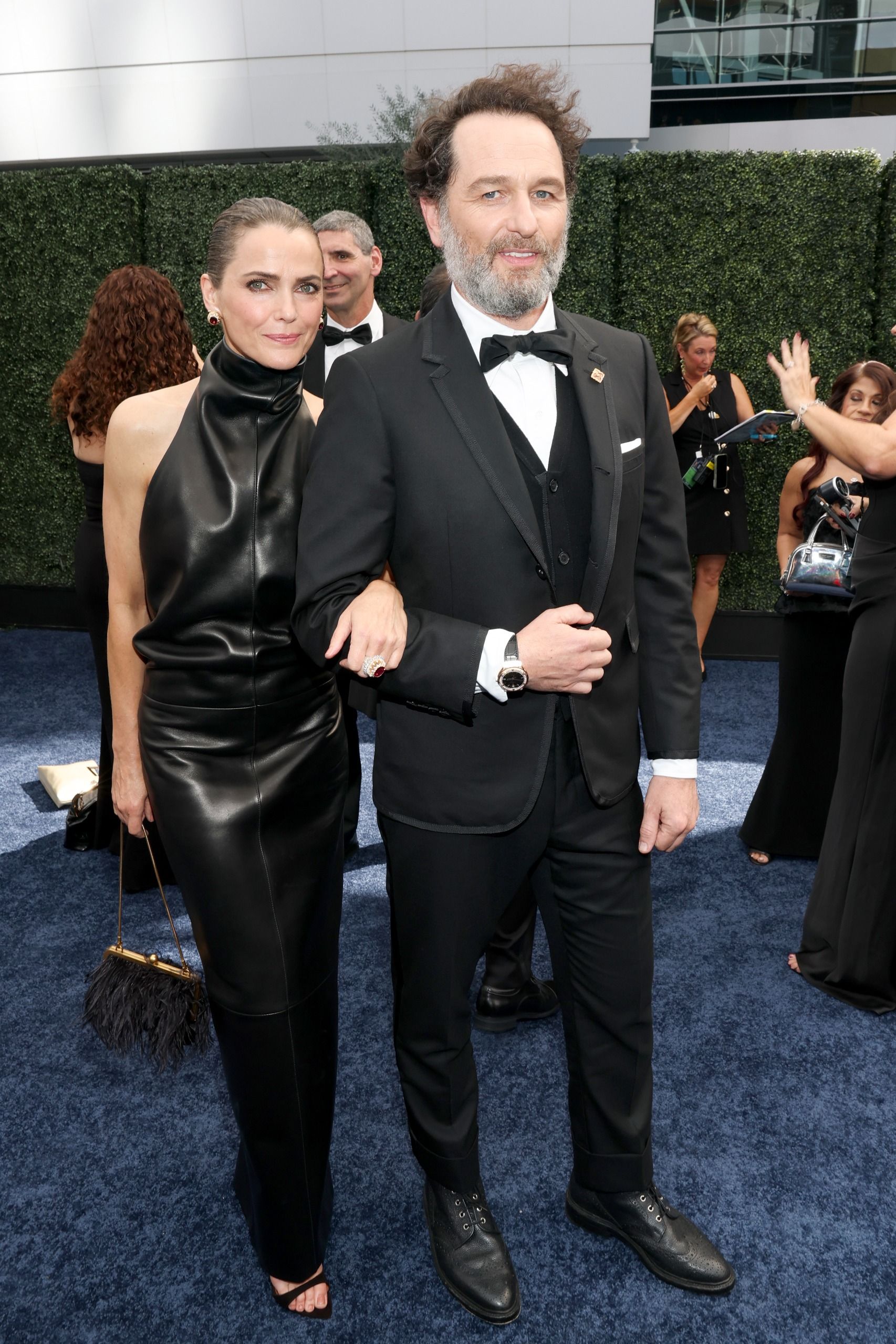 a woman in a black leather dress and a white man in a tux