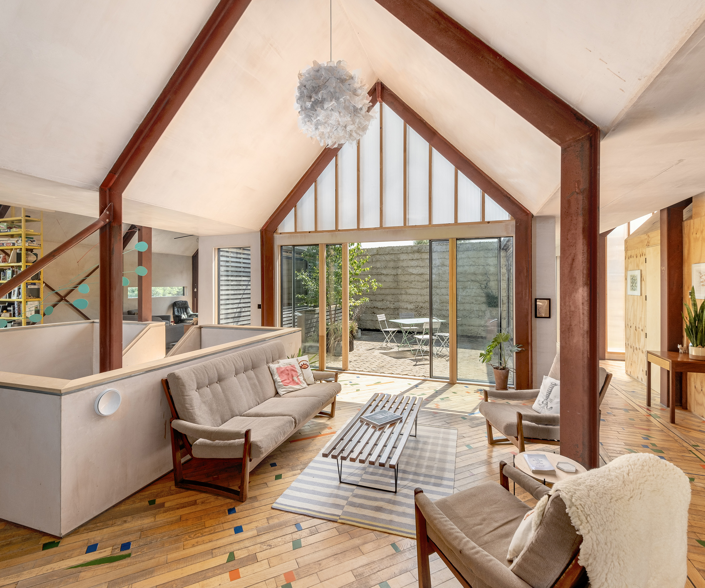 Large open plan living space in a self build home. The surfaces are all in natural materials and the furniture has a midcentury modern aesthetic