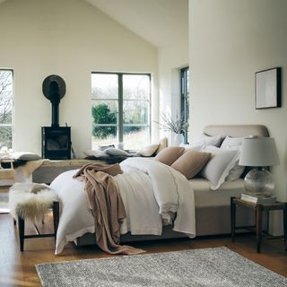 White bedding in a neutral bedroom with fireplace