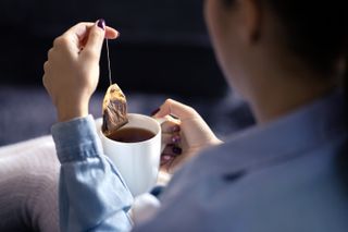 Woman dunking tea bag into a mug