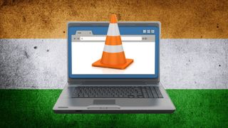 A laptop with a traffic cone coming out from the screen on the Indian flag on the background