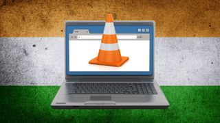 Un portátil con un cono de tráfico saliendo de la pantalla sobre la bandera india de fondo