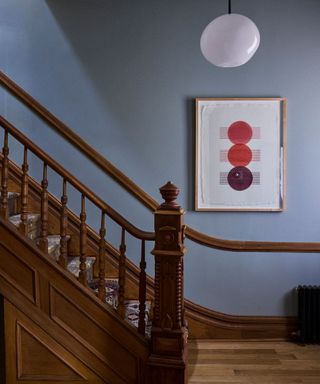 entryway with light blue walls, wooden staircase and picture rail, white pendant light and framed print