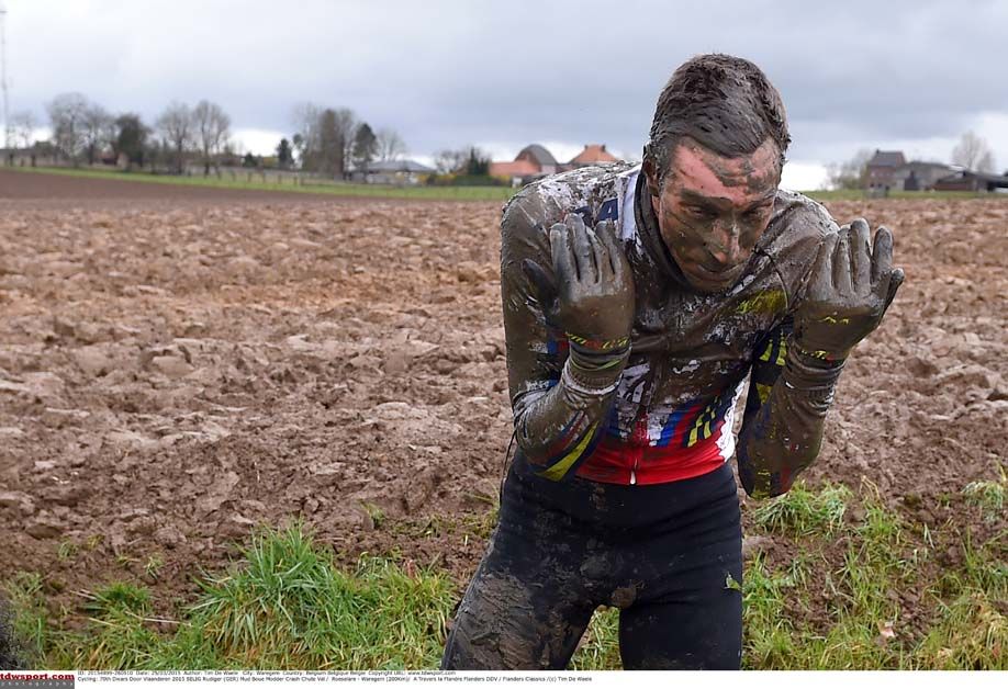 Rudi Selig clears the mud from his eyes after a crash during Dwars door Vlaanderen
