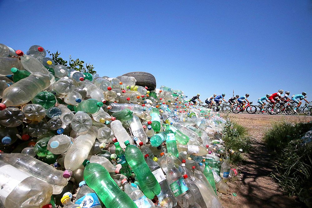 Riders race past a pile of plastic bottles