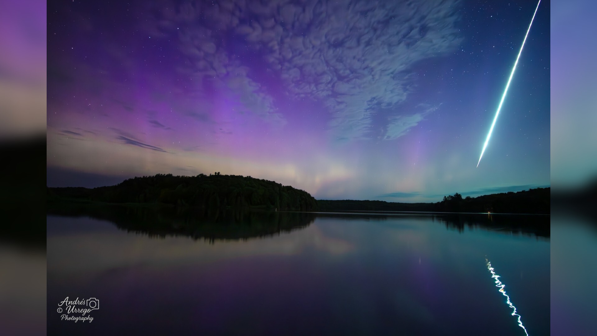 Purple and blue patterns dot the sky over a reflective surface with a streak of light running down the right side