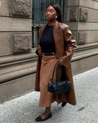 Nnenna wears suede midi skirt, leather brown coat and black ballet flats