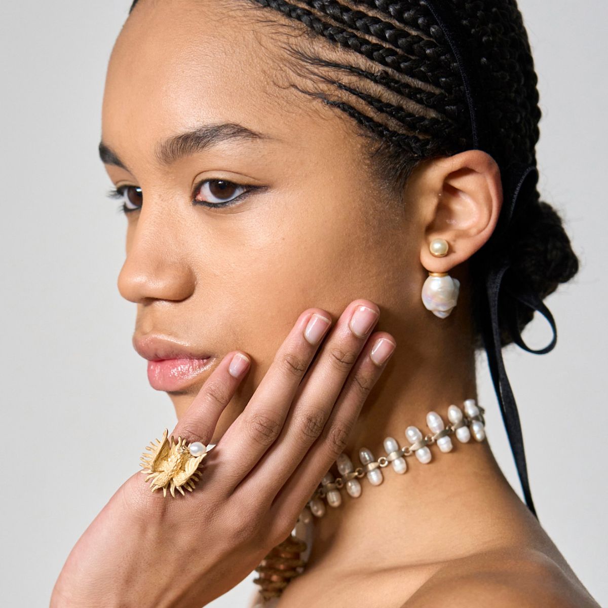 model wearing gold jewellery with plain manicured nails