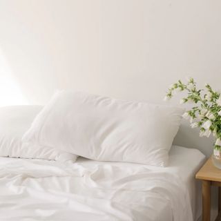 Cozy Earth Bamboo Sheet Set in white on bed with white flowers on bedside