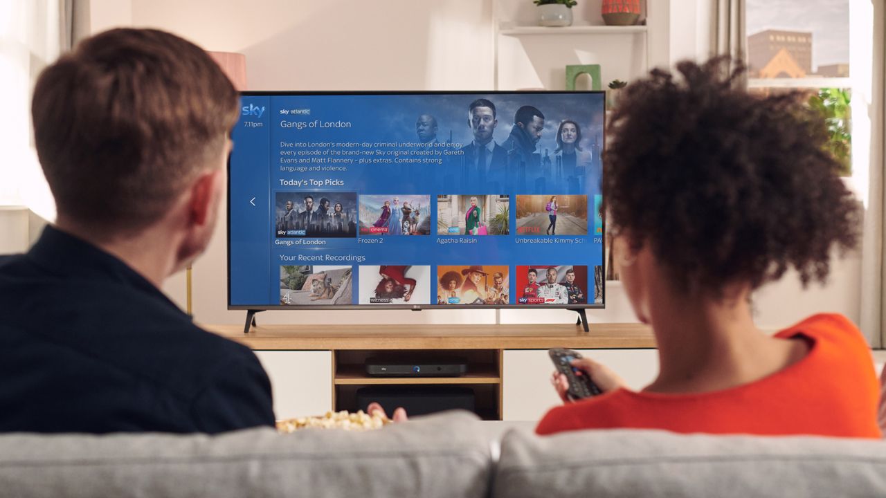 A man and a woman watch Sky TV on a Sky Q box connected to a 4K TV