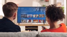 A man and a woman watch Sky TV on a Sky Q box connected to a 4K TV