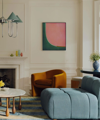 living room with a small blue sofa, burnt orange arm chair, and colorful decor