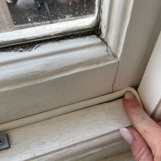 Strip of insulation tape being held in place on window frame