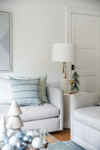 A living room with white sofas and powder blue pillows and Christmas decor