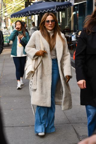 jennifer lopez wearing coat, jeans, and heels