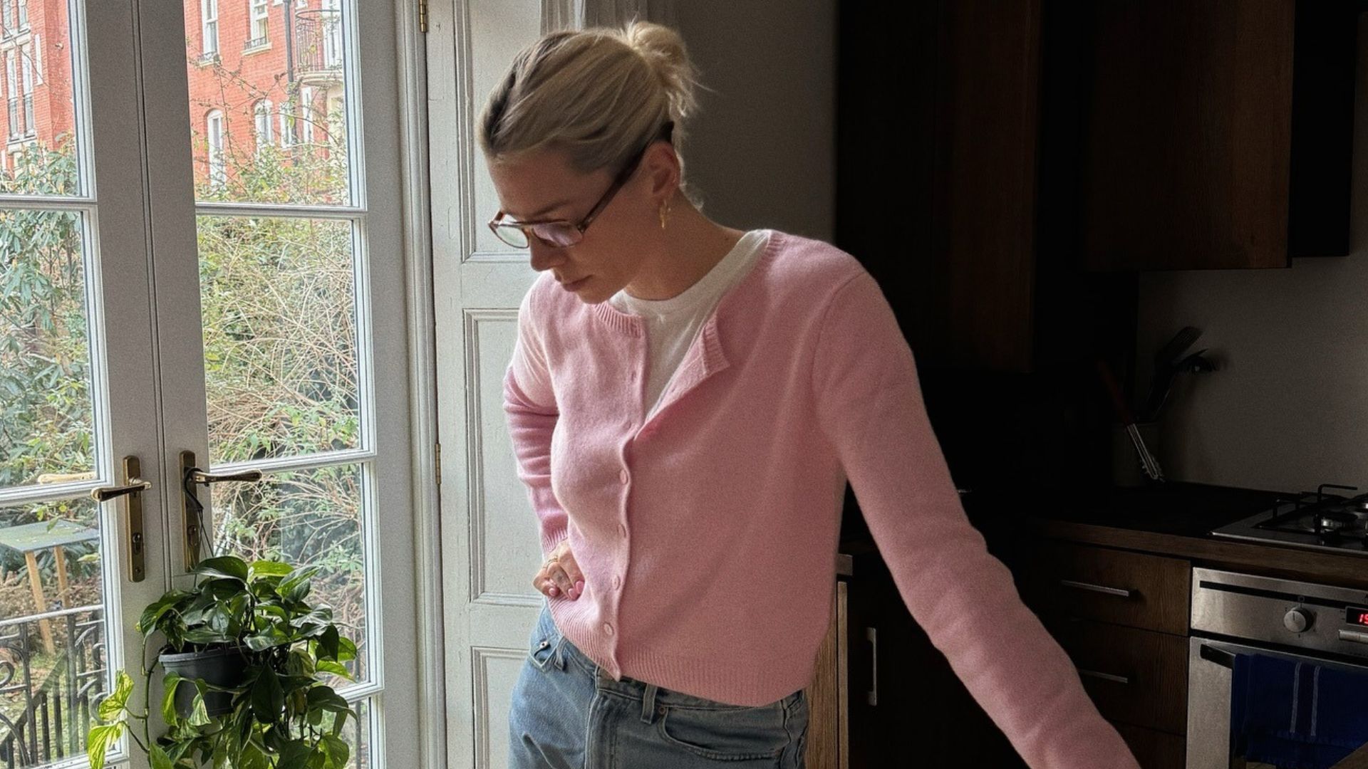 Influencer @lindseyholland_ wears a pink cardigan with blue jeans over a white t-shirt.