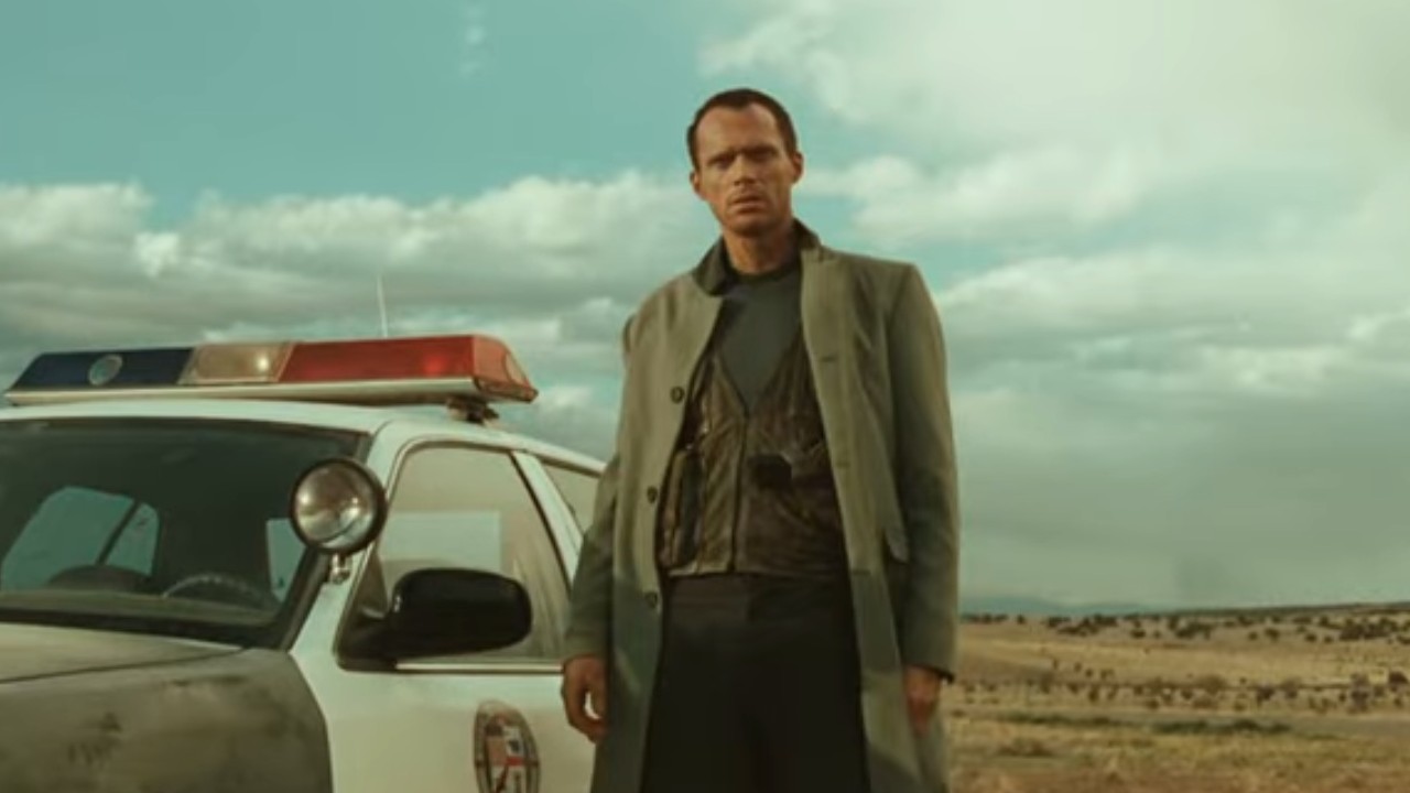 Paul Bettany standing beside a police car in Legion