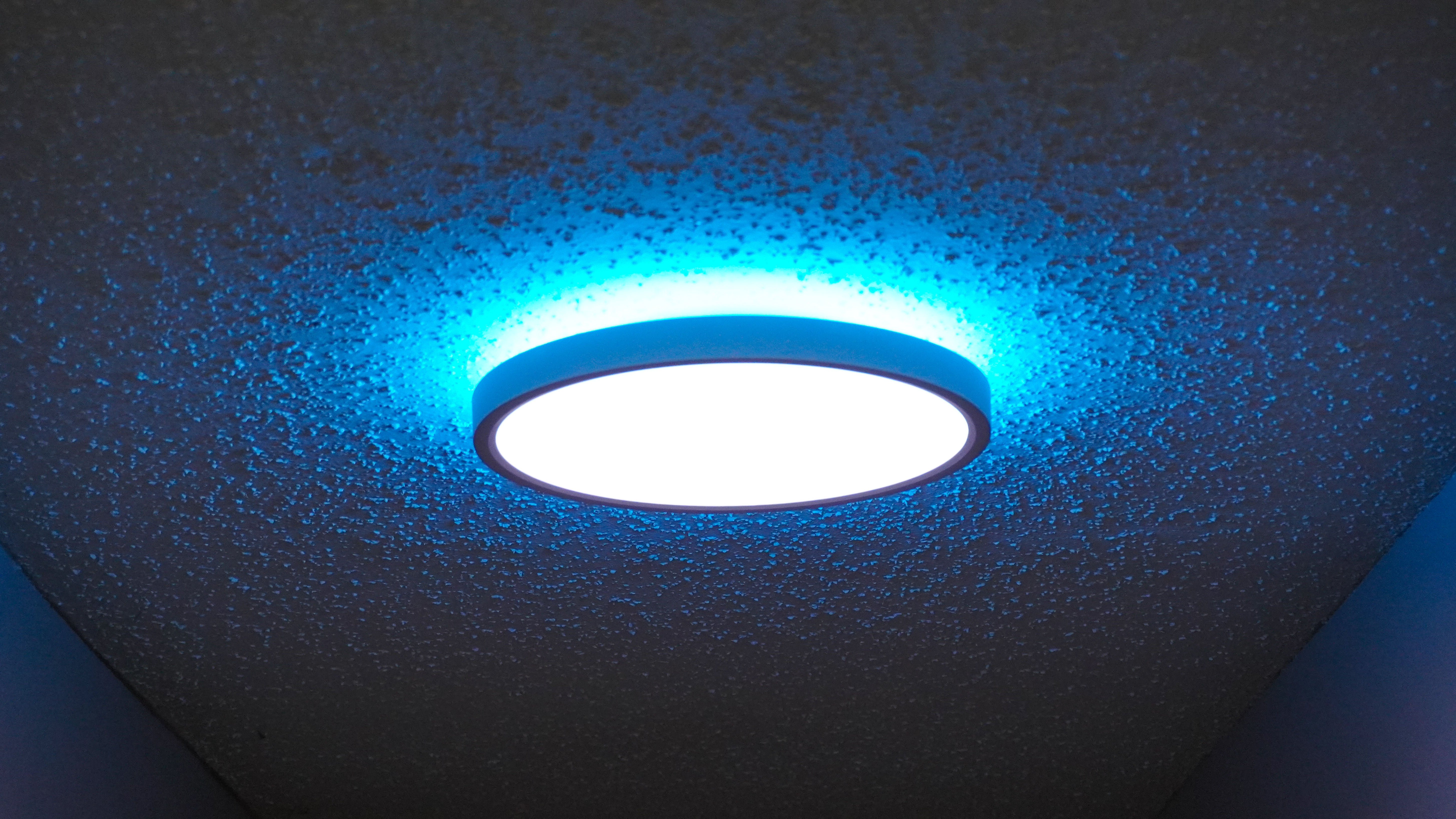 One of Govee's smart ceiling lights installed in a hallway with the main light showing white and the back light set to blue
