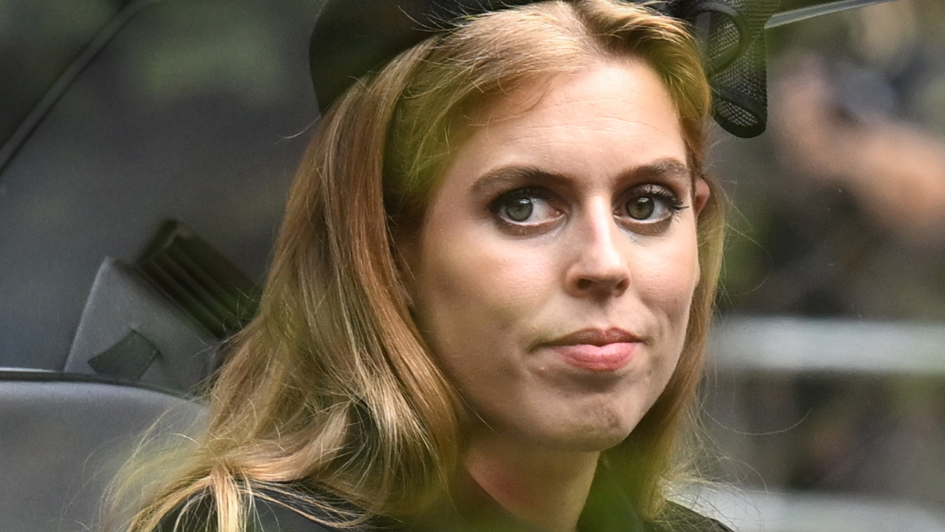 Princess Beatrice wears a black bow in her hair and a green coat