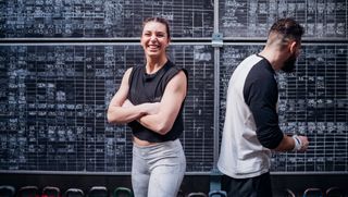 Two people in front of a black board in a gym