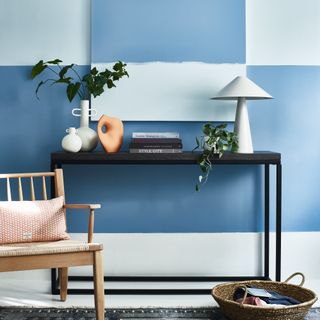Living room detail with a black console table against a half painted blue wall and artwork