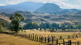 A fenced farm and the mountains of Montana