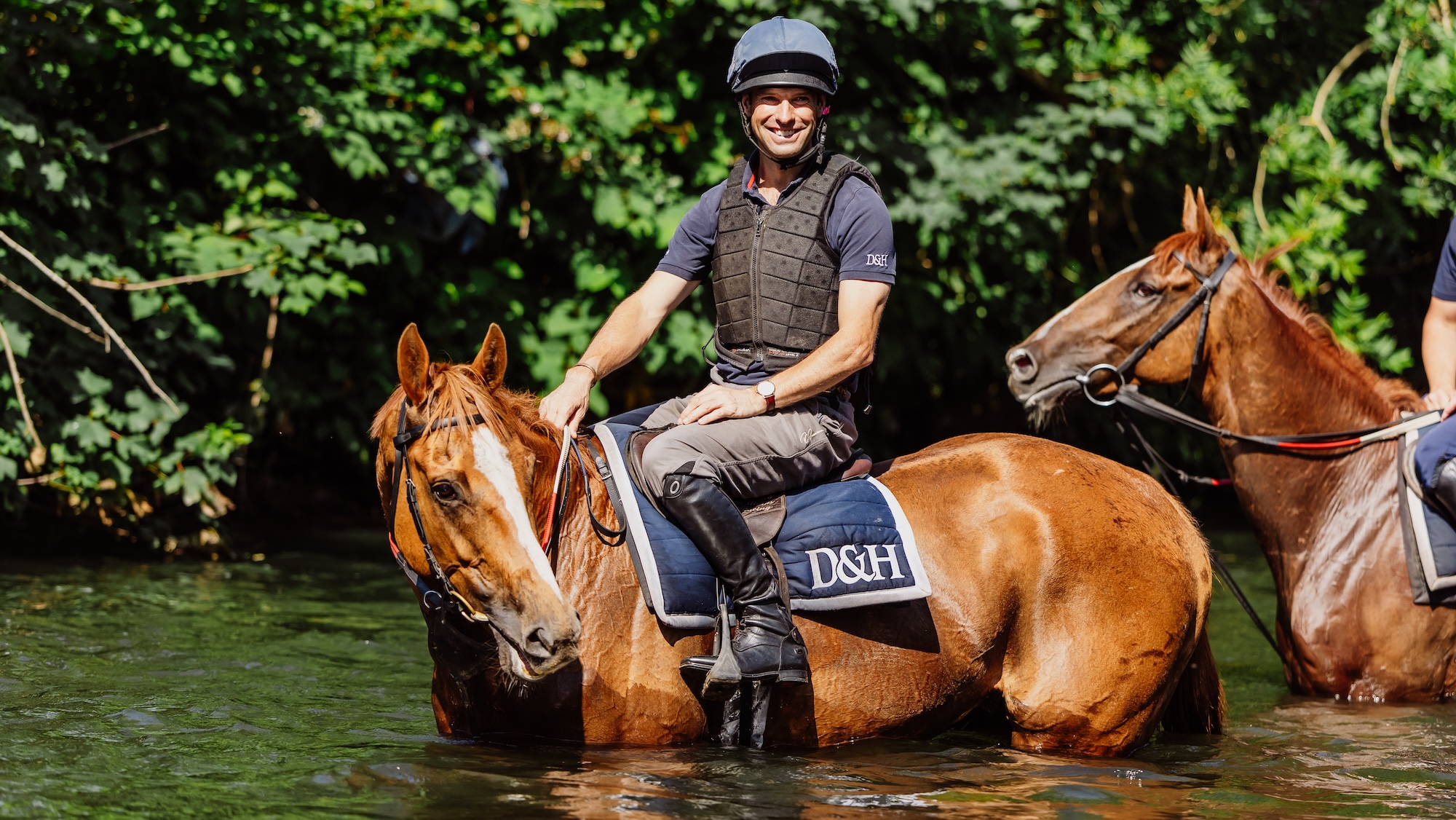 Harry Meade riding out at Christian Williams yard on chestnut horse in river