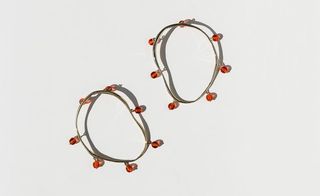 earrings with red glass beads which hang from these irregular circles of bronze metal by Faris