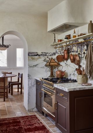Kitchen with aubergine Shaker-style cabinets, white marble countertop and splashback and off-white Roman clay walls