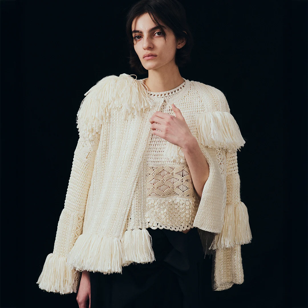 a model wearing a crochet sweater with fringe