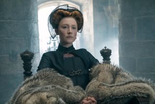 saoirse ronan as mary queen of scots as she sits on her thrown with a fur draped over her green gown