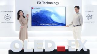 Two people standing in front of a new LG OLED EX display