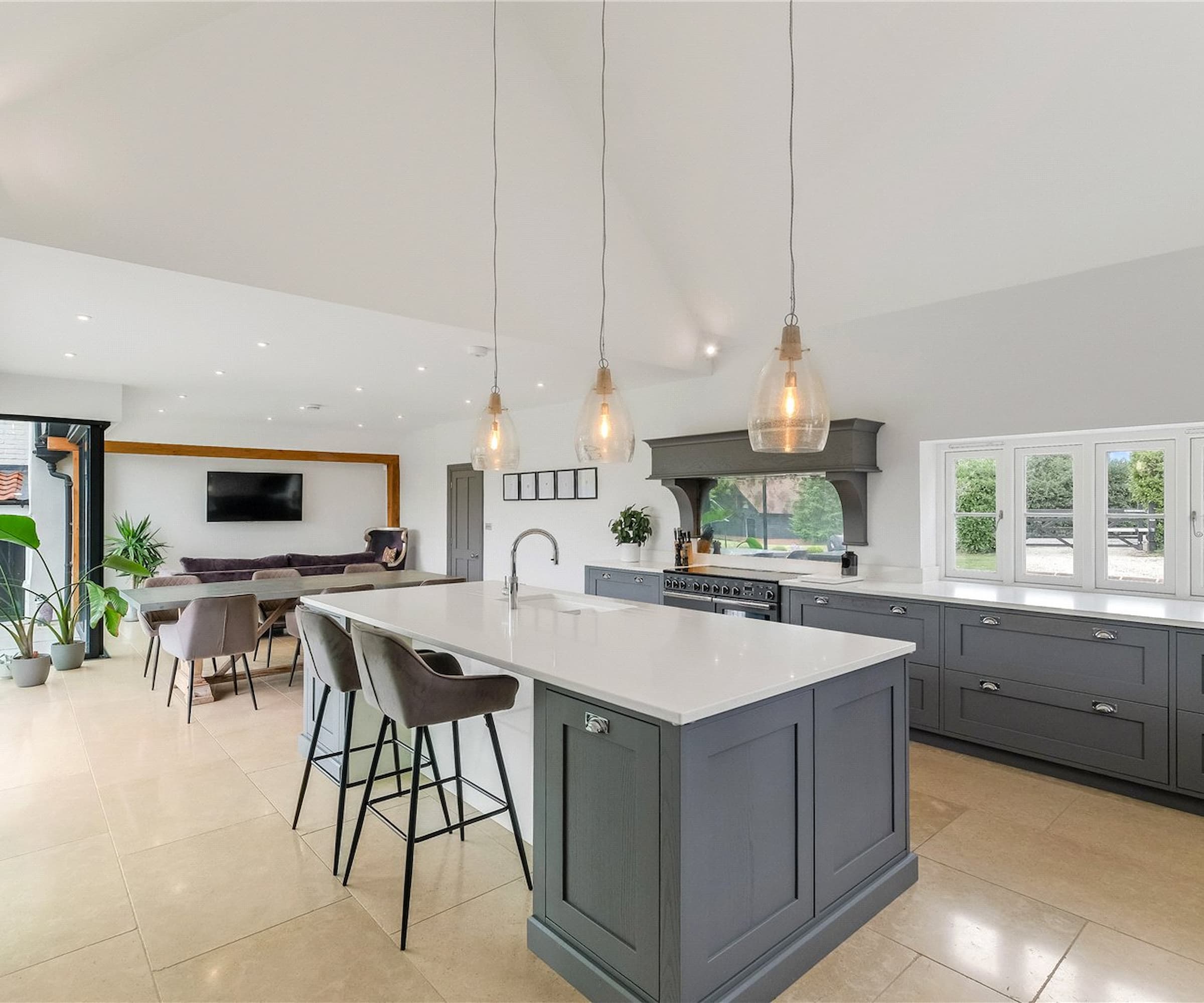 A modern kitchen with a kitchen island with a dining area with overhead lighting
