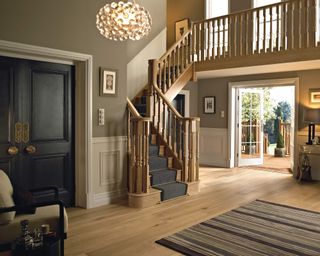 A stair railing idea by Richard Burbridge with black door, grey stair runner, striped carpet and statement pendant light